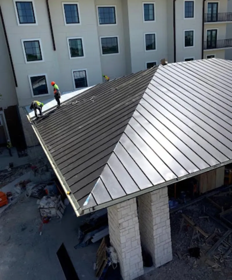 Crew installing standing seam metal roof panels on a commercial project in Bainbridge